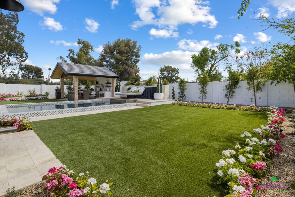 Custom backyard design with annuals, real grass and deco-tile pool.