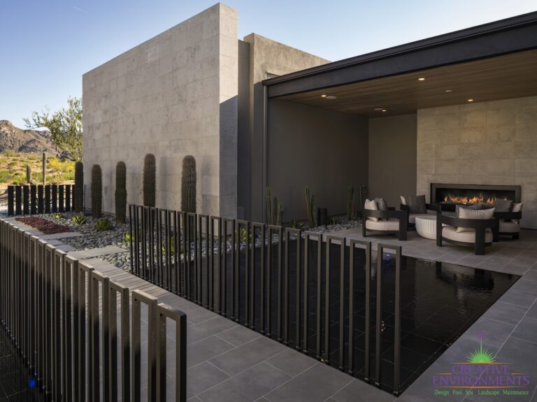 Custom front yard design with metal fencing, water feature and built-in fireplace.