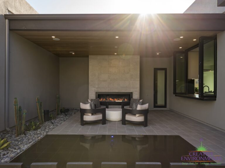 Custom seating area in front yard with fireplace, water feature and cacti.