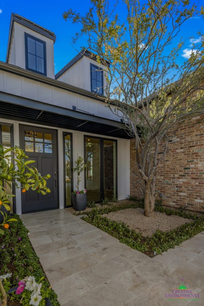 Custom front yard design with large planters, multiple trees and unique walkway.