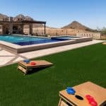 Custom backyard design with artificial turf, corn hole and metal scupper water feature.