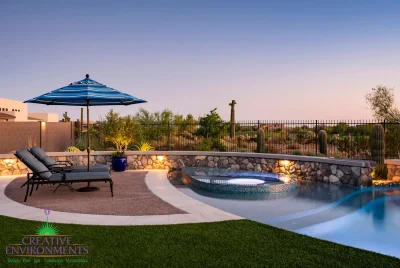 Custom backyard design with natural stone retention wall, curved pool and spa within pool.