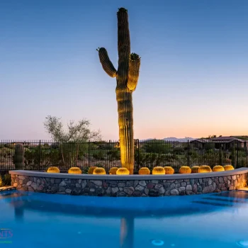 Custom backyard design with blue pool, stone retention wall and metal fencing.