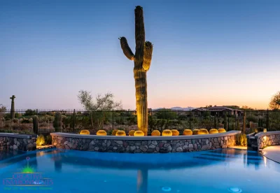 Custom backyard design with blue pool, stone retention wall and metal fencing.