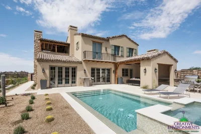 Custom backyard design with blue pool, raised spa and metal trellis.