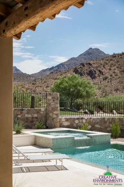 Custom backyard design with blue pool, raised spa and metal gate.