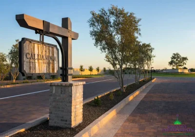 Custom community entrance with hanging sign, mixed material driveway and large water fountain.