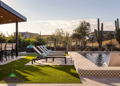 Custom backyard design with artificial turf, deco-tile pool and multiple seating areas.
