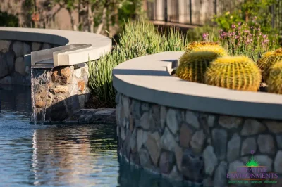 Custom backyard design with curved retention wall, curved pool and water feature into pool.