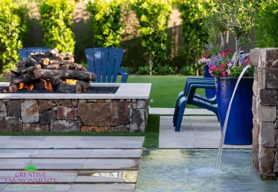 Custom backyard design with natural stone columns, Jesus steps and large, square fire pit.
