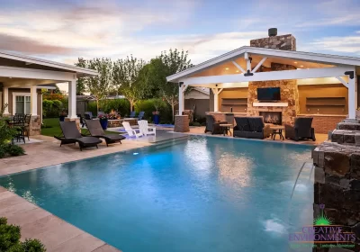 Custom backyard design with zero-edge pool, farmhouse shade structure and water columns.