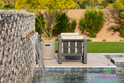 Custom backyard design with metal scupper water feature into pool, real grass and outdoor seating area.