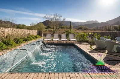 Custom backyard design with water scuppers into pool, multiple seating areas and brick deck.