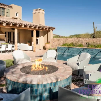 Custom backyard design with stone wall, circular fire pit and multiple seating areas.