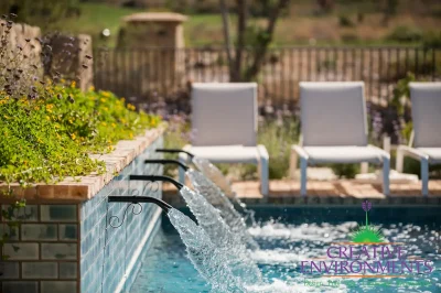 Custom metal water scuppers into pool with flowers.