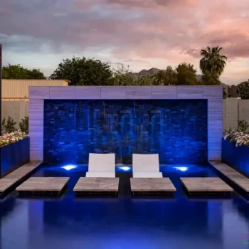 Custom backyard design with cabanas, Jesus steps and baja steps in front of water wall with blue water wall lighting.