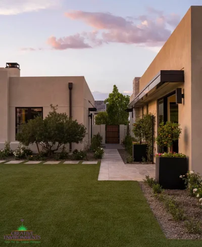 Custom backyard design with artificial turf, organized planting and large metal planters.