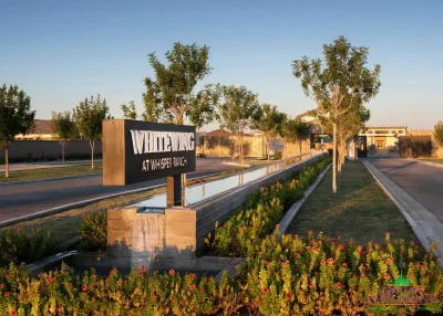 Custom community entrance with cantilevered metal entryway sign, organized planting and long water feature.