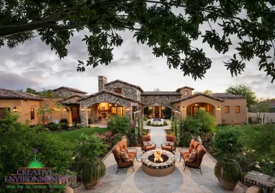 Aerial view of custom backyard design with fire pit, water feature and real grass.