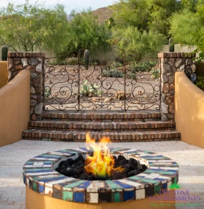 Backyard design with brick steps, fire pit and metal gate.