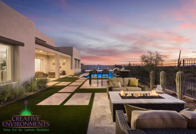 Custom backyard design with natural stone paver steps, multiple seating areas and blue pool.