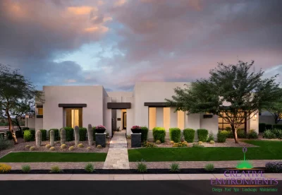 Custom front yard design with up lighting, natural stone paver walkway and artificial turf.