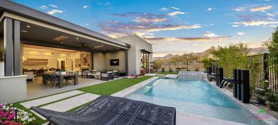 Custom backyard design with metal scupper water feature, blue pool and multiple seating areas.