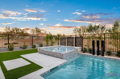 Custom backyard design with metal fencing, blue pool and artificial grass.