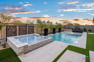 Custom backyard design with blue pool, custom metal dividers and raised spa.