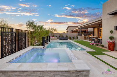 Custom backyard design with raised spa, blue pool and metal scupper water feature.