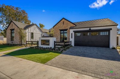 Custom front yard design with paver driveway, built-in fireplace and organized planting.