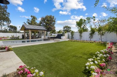 Custom backyard design with annuals, real grass and deco-tile pool.
