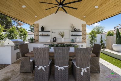 Custom backyard design with outdoor shade structure, outdoor shelving and large potted plants.