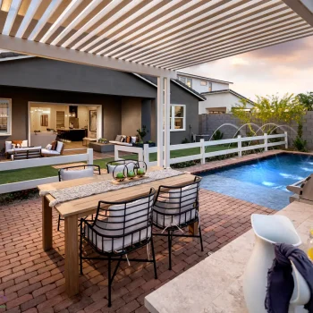 Custom backyard design with white metal shade structure, outdoor dining area and artificial turf.