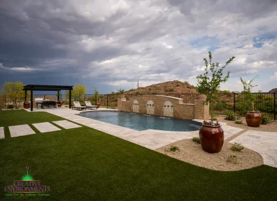 Custom backyard design with large planters, metal shade structure and metal fencing.