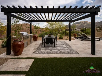 Custom backyard design with slatted metal shade structure, artificial turf and multiple seating areas.