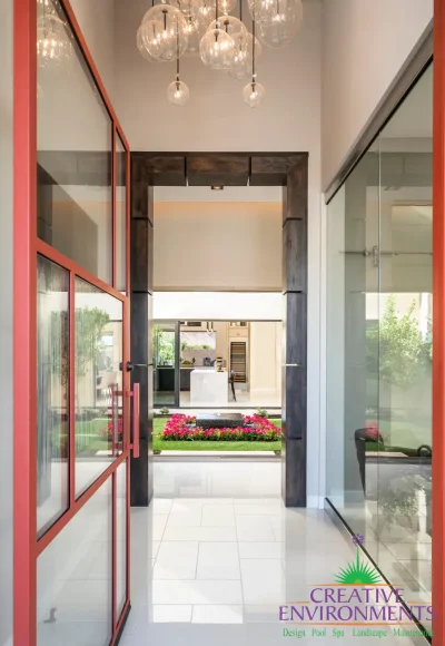 Custom indoor/outdoor design fusion with red accents and black water feature as a focal point.