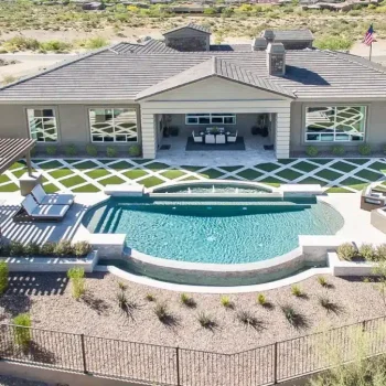 Custom backyard design with artificial turf pattern, unique shaped pool and slatted shade structure.