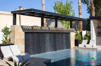 Backyard design with metal cutout shade structure over textured, black water wall into pool.