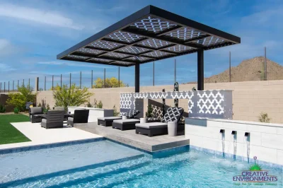 Custom backyard design with cantilevered shade structure, metal scupper water feature into pool and large baja step.