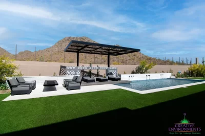 Custom backyard design with cantilevered shade structure, cantilevered fire table and blue pool.