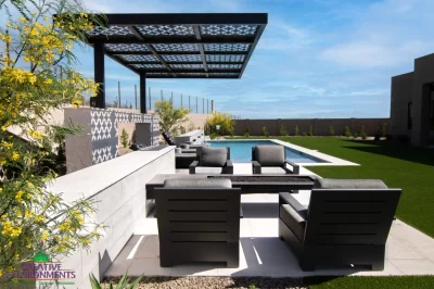 Custom backyard design with cantilevered shade structure, fire table with seating area and organized planting along the perimeter of the property.