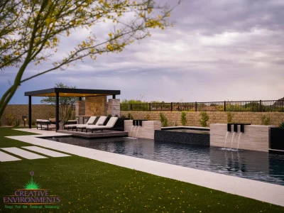 Custom backyard design with metal shade structure, raised black spa and pool.