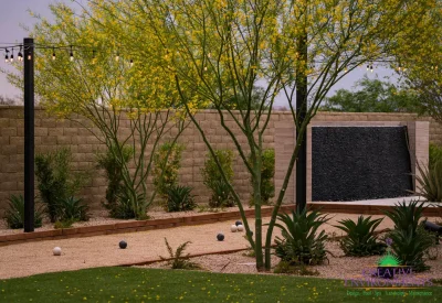 Custom backyard design with black water wall, bocce ball court and organized planting.