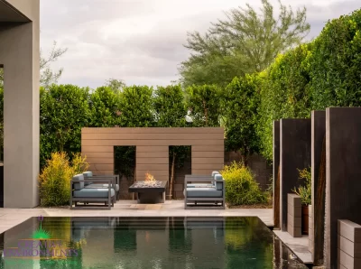 Custom backyard design with fire pit, privacy hedges and black pool.