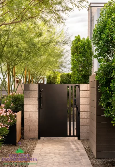 Custom backyard design with metal side gate, privacy hedges and natural stone paver walkway.
