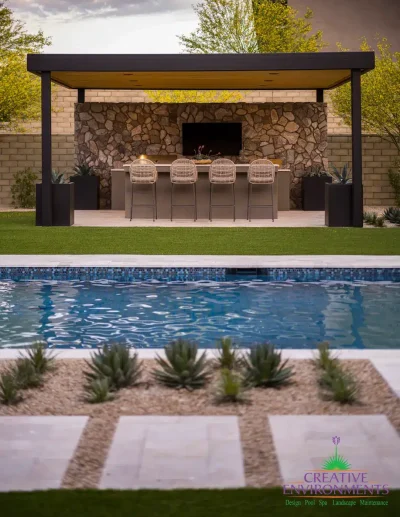 Custom backyard design with blue pool, angled shade structure and large metal planters.