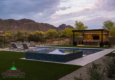 Custom backyard design with custom metal shade structure, blue spa and multiple seating areas.