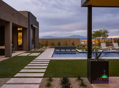 Custom backyard design with artificial turf, blue pool and raised spa.