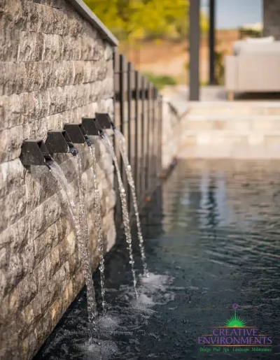 Custom metal scupper water feature into pool with slatted metal statement piece.